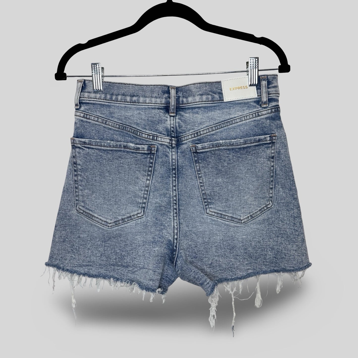 Blue denim shorts on a hanger against a gray background