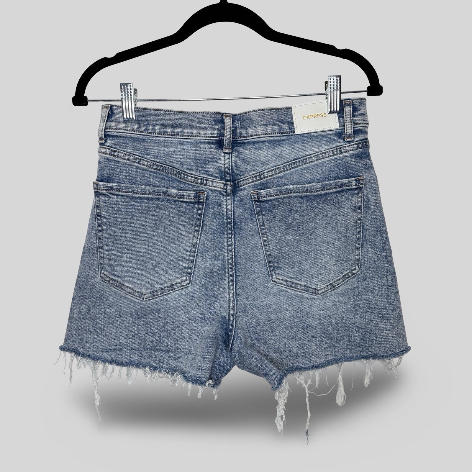 Blue denim shorts on a hanger against a gray background