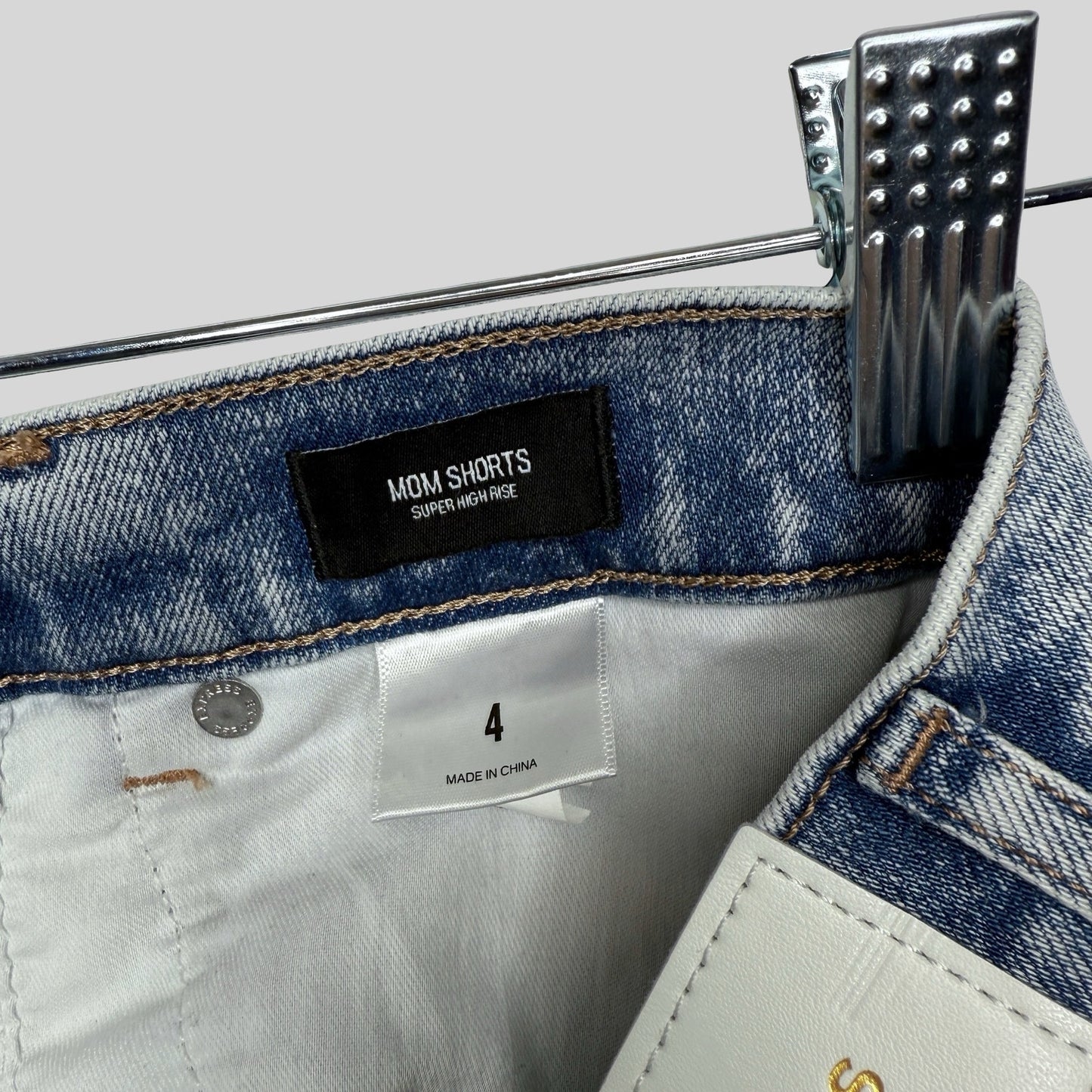 Close-up of denim mom shorts with a label on a gray background