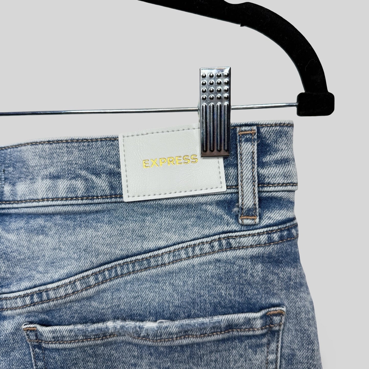 Blue jeans shorts with a visible 'Express' label on a hanger against a light gray background