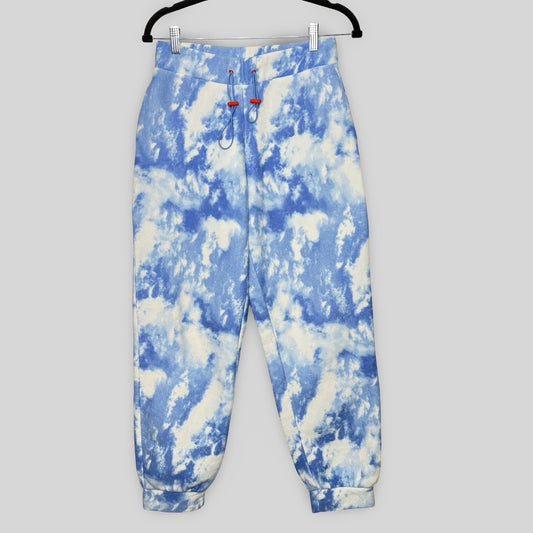 Blue and white tie-dye pants on a hanger against a gray background